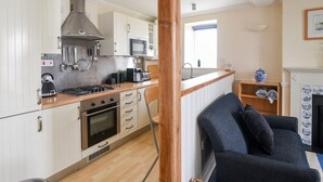 Une cuisine de taille réduite avec des meubles blancs, un four à micro-ondes, une cuisinière et un grille-pain.