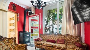 A living room with a patterned sofa, a wooden cabinet, and a chandelier. - Villa Maria and Dimosthenis with Garden & Wi-Fi (Kalamata)