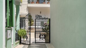 A narrow alleyway with a gated entrance, potted plants, and a tiled floor. - Villa Maria and Dimosthenis with Garden & Wi-Fi (Kalamata)