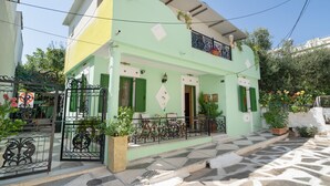 A two-story building with a balcony, a tiled entrance, and potted plants. - Villa Maria and Dimosthenis with Garden & Wi-Fi (Kalamata)