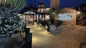 Un edificio con una imponente torre de reloj, un cartel que dice 'Queen Mississippi' y una entrada bien iluminada.