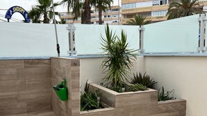Una terraza en la azotea con jardineras de madera, un regador verde y un arco temático de Snoopy.