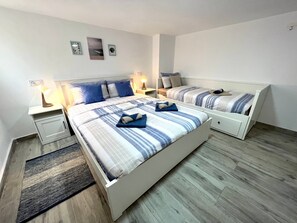 Un letto matrimoniale con copriletto a righe, due comodini con lampade, un tavolino e un piccolo tappeto.