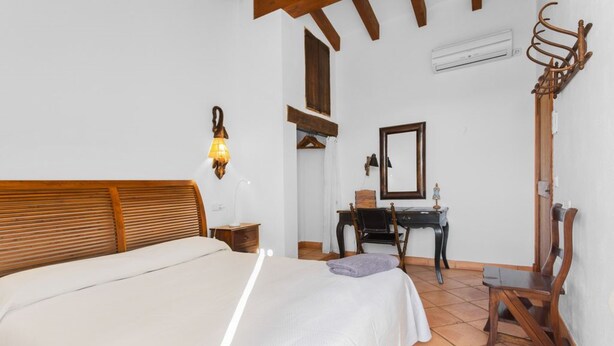 Une chambre à coucher comprenant un lit, un bureau, une chaise, un miroir et un porte-manteau.