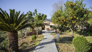 A stone pathway leading to a rustic house with a tiled roof, surrounded by lush greenery and citrus trees. - Holiday Home "Es Tarongers" with Mountain View, Garden, Terrace & Pool (Sóller)