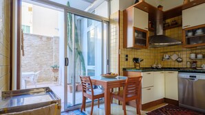 Una cocina con mesa y sillas, lavavajillas y una puerta corrediza de vidrio que da a un espacio exterior.