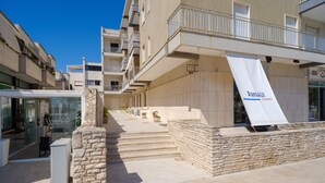 Un edificio moderno con fachada de piedra, un banderín y una escalera que conduce a un nivel superior.