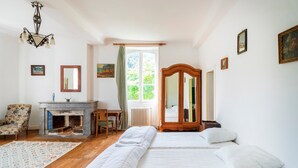 Une chambre à coucher avec un lit, une armoire en bois, un bureau, une chaise et une cheminée.