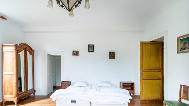 A bedroom with a wooden bed, a wooden wardrobe, a wooden chair, and a door. - Etxeparea – Family Home with Wi-Fi in the Basque Country (Ustaritz)