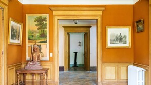 Un couloir orné d’une statue, de tableaux encadrés et d’un radiateur.