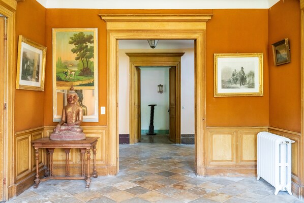 Un couloir orné d’une statue, de tableaux encadrés et d’un radiateur.