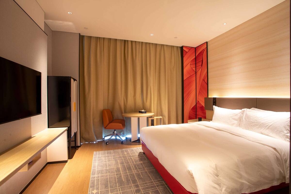 Habitación de hotel con una cama grande, televisión de pantalla plana, escritorio con silla y una mesita.
