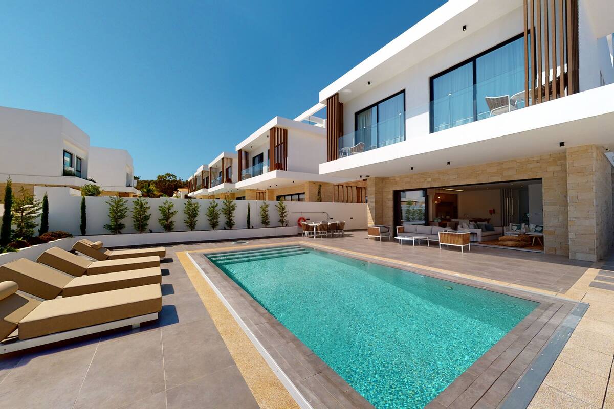 Un espace piscine extérieur moderne, doté de chaises longues et d’un ensemble de mobilier de jardin.