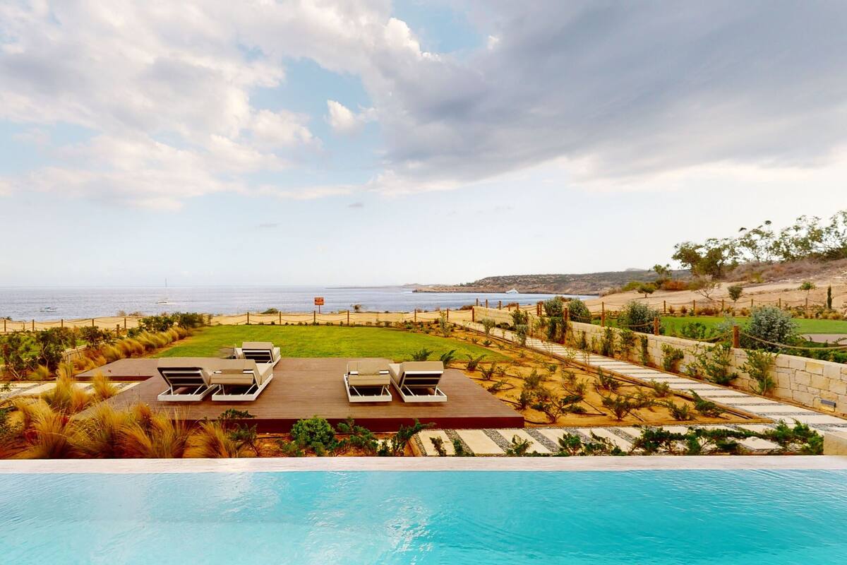 Un espace aménagé au bord de la piscine, avec des chaises longues et une vue sur l’océan.