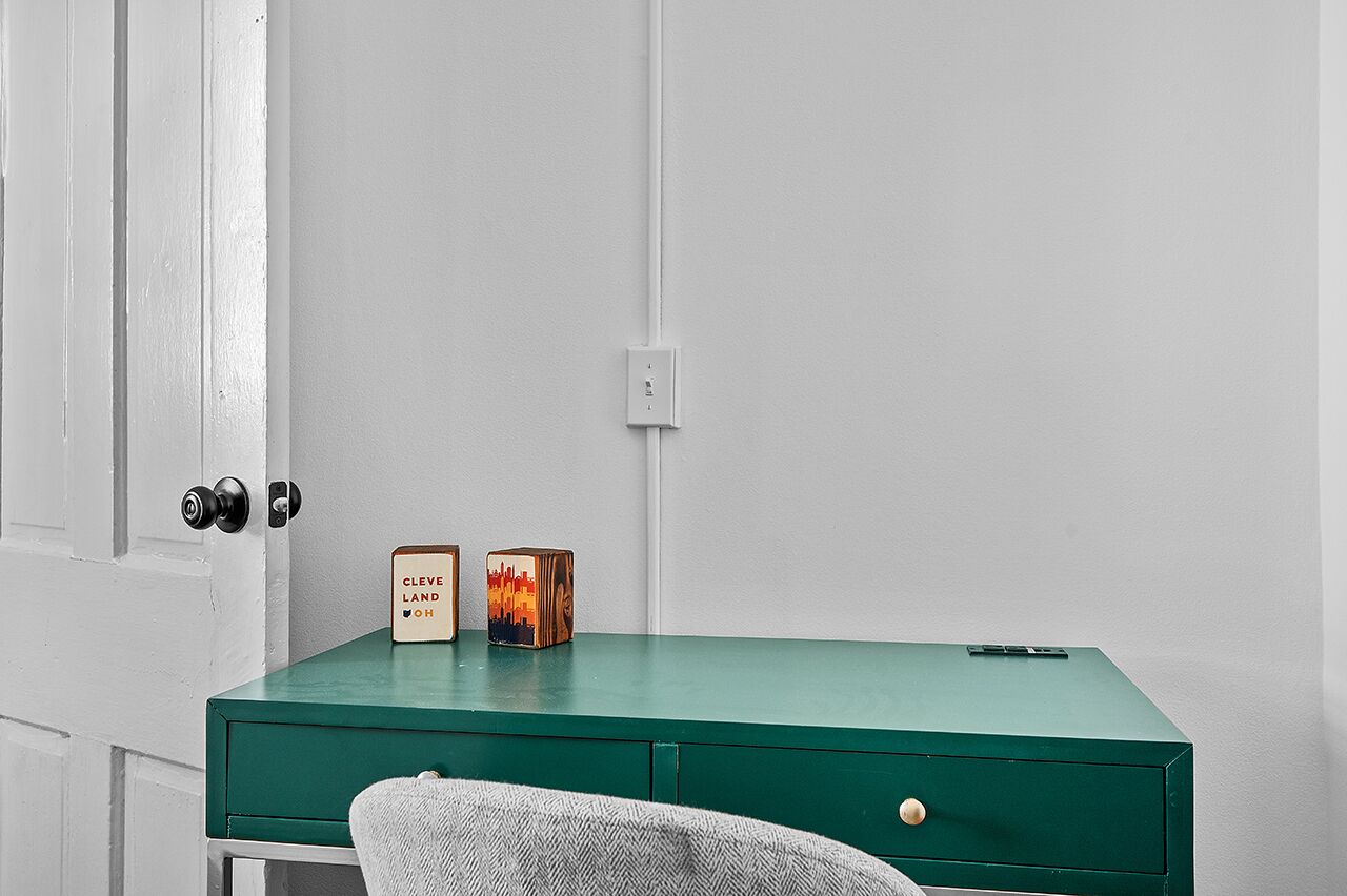 Un bureau vert avec deux blocs de bois, une porte avec une serrure et un mur blanc.
