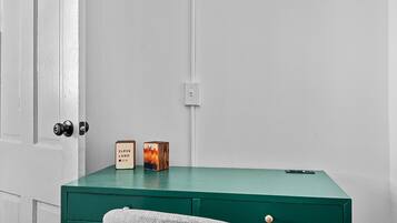 Un bureau vert avec deux blocs de bois, une porte avec une serrure et un mur blanc.