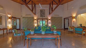 A spacious living area with a wooden ceiling, a central sofa set, and a dining table.