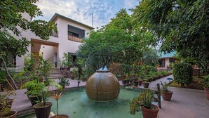 Un patio central con una fuente, rodeado de plantas en macetas y un edificio con balcones.