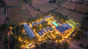 Vista aérea de una extensa propiedad bien iluminada, con varios edificios, piscina y campos circundantes.