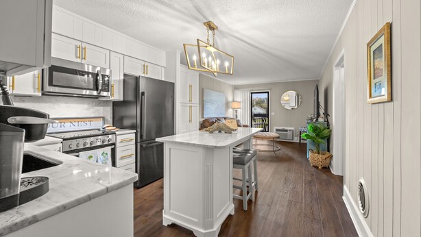 A modern kitchen with white cabinetry, stainless steel appliances, and a marble countertop.