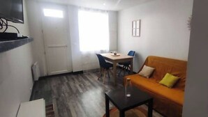 Un espai vital compacte amb un sofà, una taula petita, una cadira i una televisió.