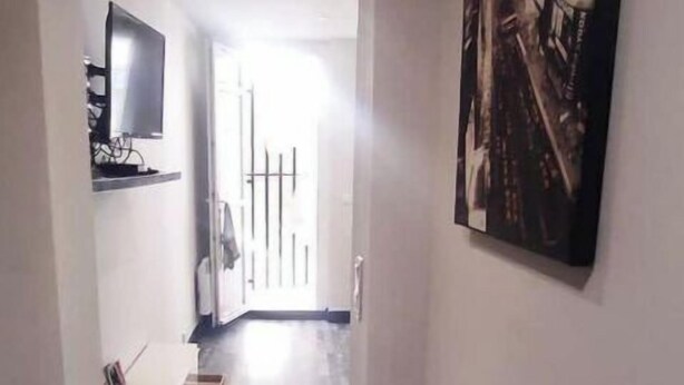 Un passadís estret amb un paviment estampat, un televisor penjat i una obra d'art emmarcada a la paret.