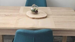 Taula de dinar amb fusta, un centre de taula de vidre i una cadira tapissada de blau.