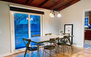 Un comedor con una mesa y sillas, una planta en maceta y un cuadro en la pared.