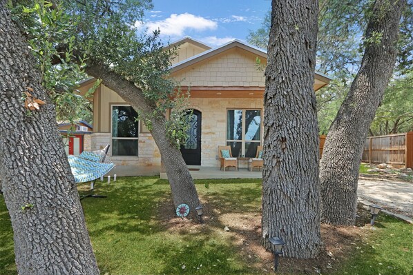 A house with a stone facade, large windows, and a covered patio area.