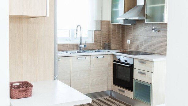 A compact kitchen with light wood cabinets, a stainless steel sink, and a modern stove. - Delightful Apartment with amazing view (Elliniko-Argyroupoli)