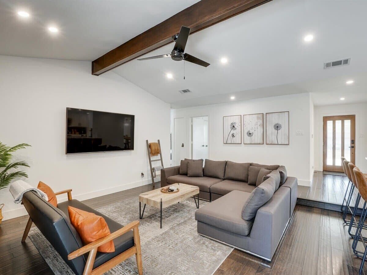 Un salon moderne avec un canapé d’angle, une table basse et un téléviseur fixé au mur.