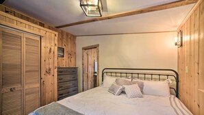 Een slaapkamer met een bed, houten wanden, een dressoir en een nachtkastje.