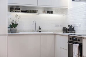 A modern kitchen with white cabinetry, a built-in sink, and a coffee maker.