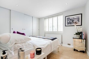 A bedroom with a bed, bedside table, and a window with blinds.