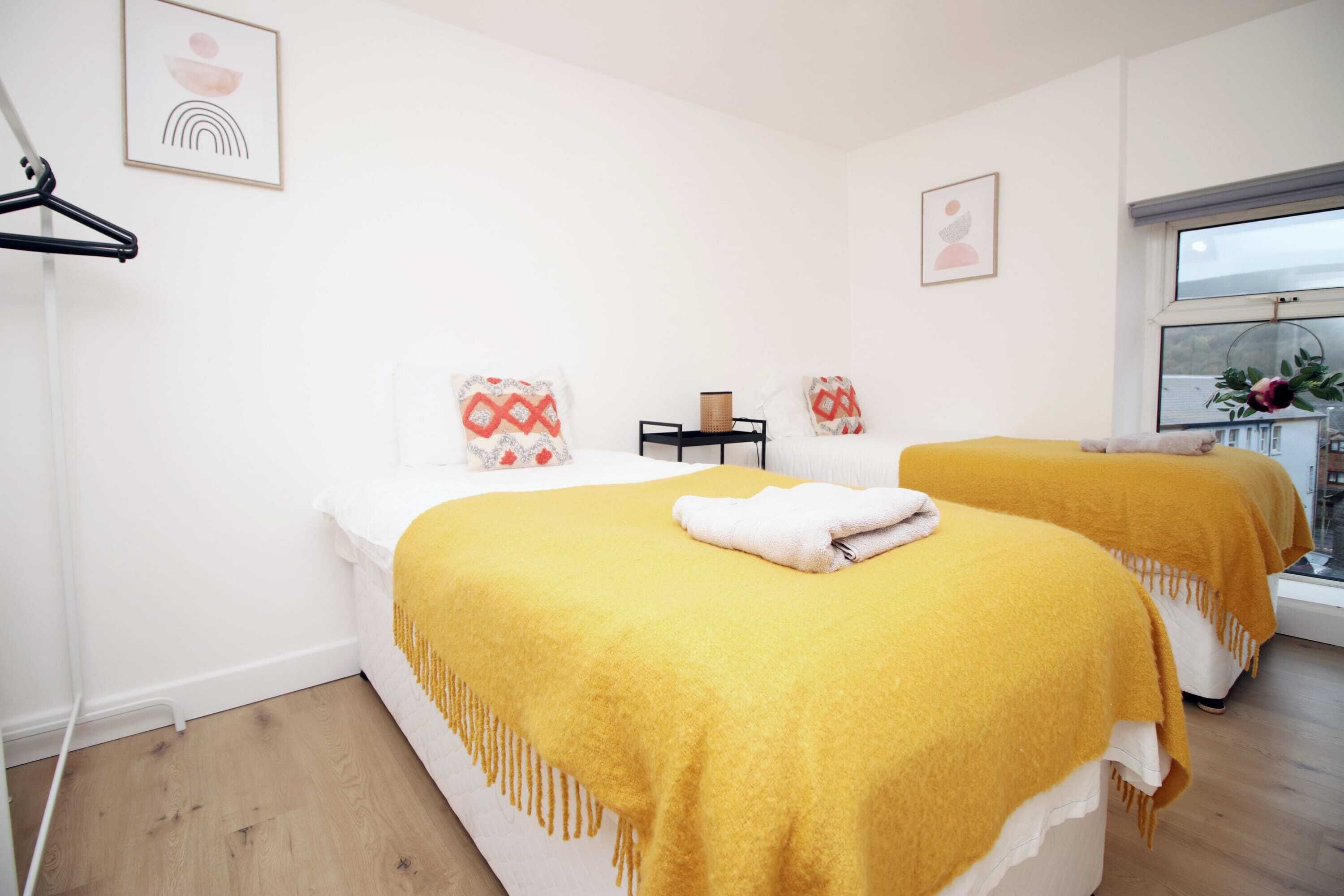 A hotel room with two beds, a window, and a wall-mounted towel rack.