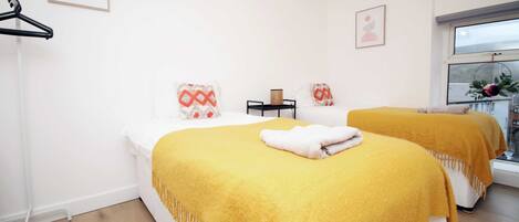 A hotel room with two beds, a window, and a wall-mounted towel rack.