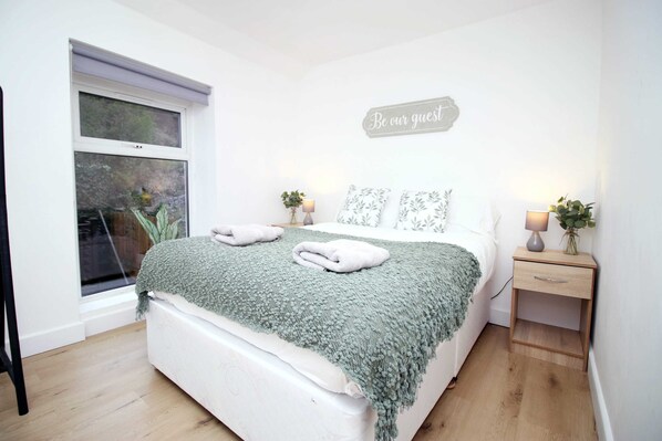 Relax in a spacious room with a large bed, bedside table, and potted plant.
