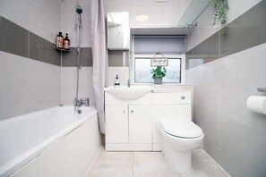 Enjoy a refreshing shower in the bathroom, which features a sink, toilet, and showerhead.