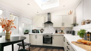 Une cuisine moderne avec des meubles blancs, une cuisinière noire et un coin repas comprenant une table et des chaises.