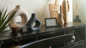 Een zwart bureau met vazen, een lijst en een klein klokje.