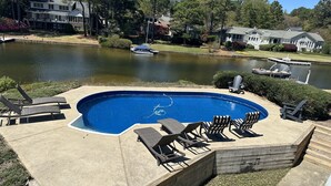 A swimming pool with lounge chairs and a dock by a lake, surrounded by houses and trees. - Pinehurst Lake House Retreat - Pinehurst Lake Front Property With a Pool (Pinehurst)