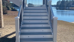 A staircase with white railings leading to a deck overlooking a body of water. - Pinehurst Lake House Retreat - Pinehurst Lake Front Property With a Pool (Pinehurst)