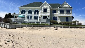 A two-story house with a covered porch and a sandy beach in front. - Huge Cape Cod Style Home on all Sandy beach / Cedar Lake MI (Oscoda)