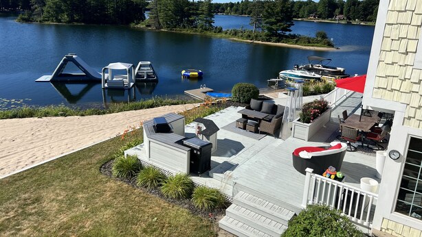 A lakeside patio with outdoor furniture, a boat dock, and a small shed. - Huge Cape Cod Style Home on all Sandy beach / Cedar Lake MI (Oscoda)