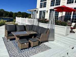 A patio with a wicker sectional sofa, a glass-top table, and a red umbrella.