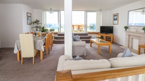 Un salon spacieux comprenant un canapé, une table basse, un téléviseur et un coin repas avec des chaises et une table.
