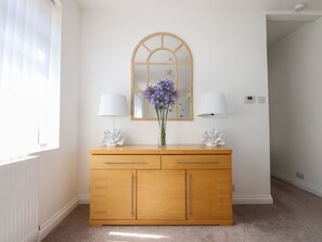 A wooden dresser with two drawers and a mirror above it. There are two lamps on either side of the dresser.