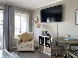 A cozy living room with a sofa, a small table, a TV, and a bookshelf. - Oceanfront - Admiral's Row 106-Professionally Managed by HHIB&T Vacation Rentals (Hilton Head Island)