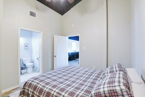Ein Schlafzimmer mit Bett, einer Tür zu einem Badezimmer und Blick auf eine Küchenzeile.