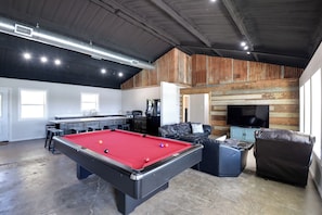 Relax in a spacious indoor recreational area with a pool table, comfortable seating, and a TV.